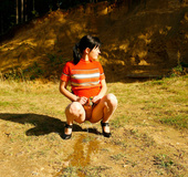 Cute tart walking down the hill squats down to pee