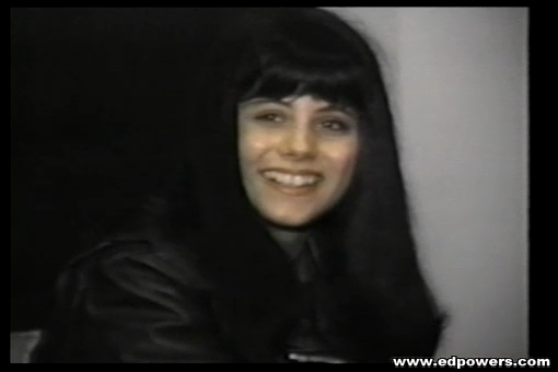 Gorgeous chick wearing black leather jacket, shirt, skirt and stockings smoking while sitting on a gray couch then talks about doing some adult modelling. - XXXonXXX - Pic 5