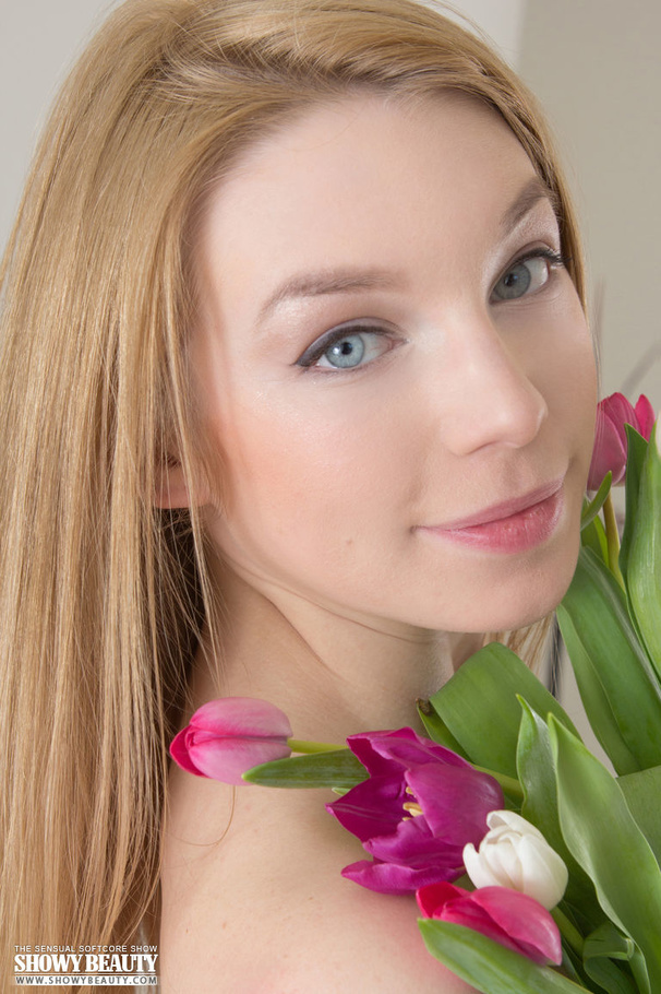 Doll faced blonde slowly removes her blue blouse, pink stockings and lingerie then seduces with her stunning body with sweet small boobs and bushy hole while she pose naked on a white and gray couch while holding some flowers. - XXXonXXX - Pic 19