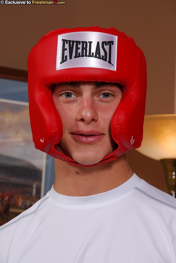 Boxing champ takes off his white shirt and shorts then displays his hunk body wearing his red head gear, blue cycling shorts and black gloves before he gets naked and bares his hard cock in different poses on a brown couch. - XXXonXXX - Pic 1