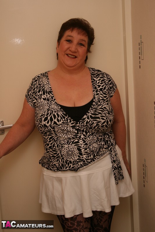 Mature chick teases with her chubby body black and white blouse, white skirt, black bra, white panty, black stockings and white high heels before she gets naked and bares her monster tits and indulging pussy in different poses on a gray stairway. - XXXonXXX - Pic 1