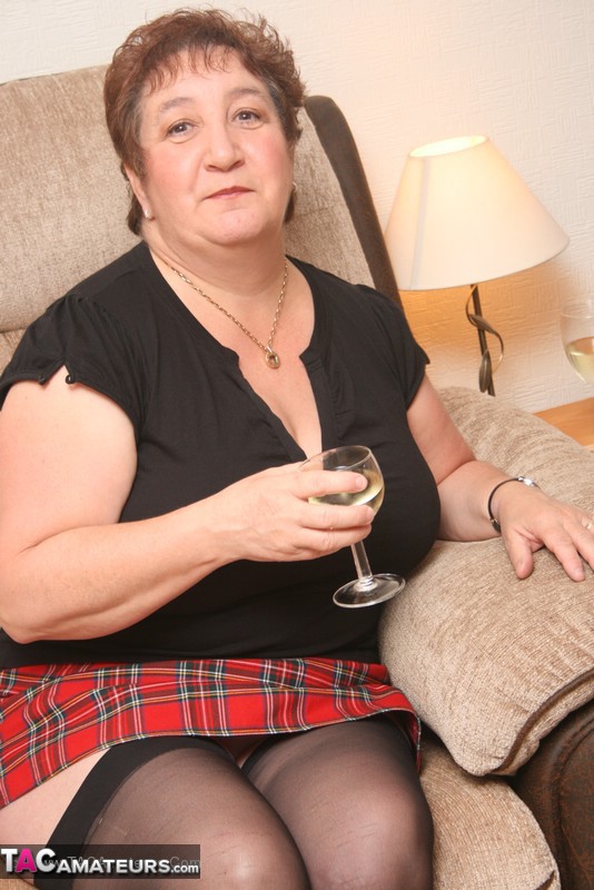 Mature babe peels off her black shirt and red skirt then teases with her super size body in different poses wearing her white lingerie, black stockings and high heels on a brown couch. - XXXonXXX - Pic 2