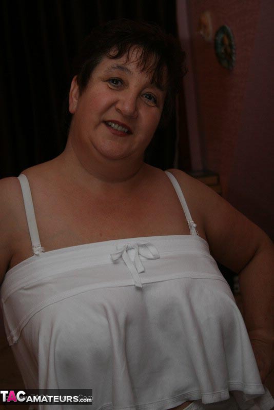 Mature BBW teases her horny hubby with her large body in white dress, lingerie, stockings and black high heels before she gets on her knees and wanks his cock on a brown bed. - XXXonXXX - Pic 4