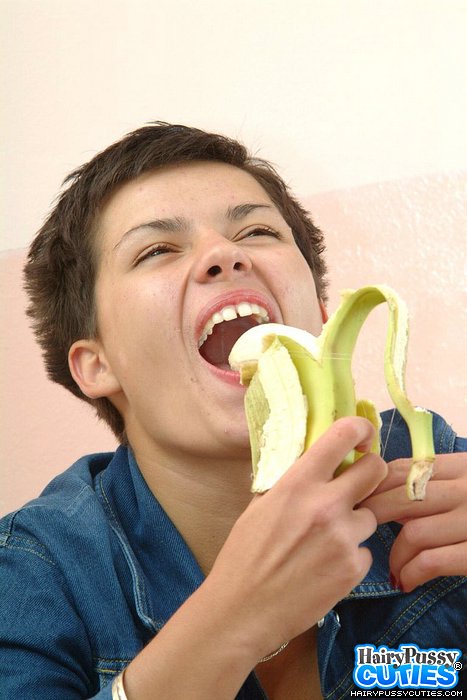 Red nailed brunette with short hair and pierced belly eating banana before undressing on the table and fingering her hairy holes - XXXonXXX - Pic 1