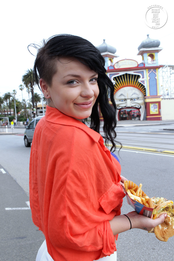 Foxy chick displays her smoking hot body while she eats her burger and fries as she walks around the street wearing her orange shirt, puple bra, white shorts and black high heels. - XXXonXXX - Pic 15