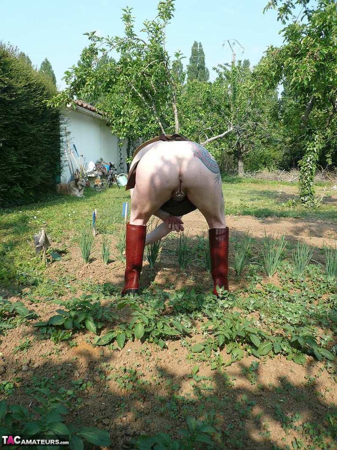 Dark haired wife with huge hooters working in the garden and showing her shaved pussy while posing in rubber boots - XXXonXXX - Pic 7