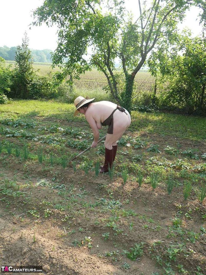 Dark haired wife with huge hooters working in the garden and showing her shaved pussy while posing in rubber boots - XXXonXXX - Pic 10