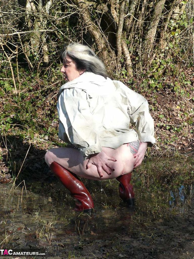 Mature gal in rubber boots sheds her coat before covering her naked body with mud and peeing in the puddle - XXXonXXX - Pic 4