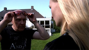 Blonde teen with long hair and in black T-shirt gives head to an old guy outdoors