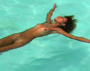 Lovely exotic beauty swimming naked in the pool demonstrating her plastic body