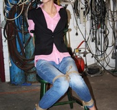 Ponytailed chick in jeans and jacket gets tied up to the chair waiting