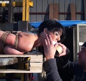 Naked brunette gal gets gagballed and bound facedown on the electric car