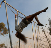 Long-haired blonde chick in a striped blouse swinging on the swings and
