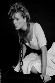 Hot babe in a modest dress posing in collar and chain for cool black and white photo session