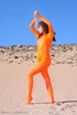 Brunette in orange latex jumpsuit shows her perfect titties