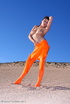 Brunette in orange latex jumpsuit shows her perfect titties