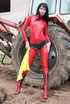 Black haired babe in red latex posing with a tractor