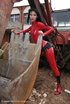 Black haired babe in red latex posing with a tractor
