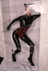 Sexy brunette in black latex jumpsuit takes on red mask