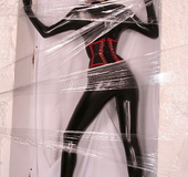 Sexy brunette in black latex jumpsuit takes on red mask