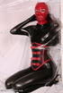 Sexy brunette in black latex jumpsuit takes on red mask