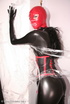 Sexy brunette in black latex jumpsuit takes on red mask
