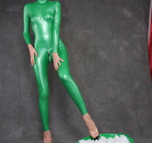 Busty babe in green latex jumpsuit posing with a bowl