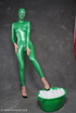 Busty babe in green latex jumpsuit posing with a bowl
