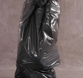 Masked girl in yellow latex comes out of a black sack and reveals her