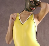 Masked girl in yellow latex comes out of a black sack and reveals her