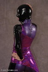 Masked girl in black and lilac latex jumpsuit posing and shows her pretty