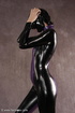 Masked girl in black and lilac latex jumpsuit posing and shows her pretty