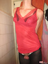 Young crossdresser in red negligee and black pantyhose ties hands to jerk
