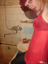 Young crossdresser in red negligee and black pantyhose ties hands to jerk