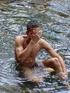 A bronzed lusty latino plays naked in the waters of a brook showing how