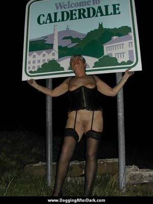 Old whore in stockings and a corset waiting for clients under the road sign - Picture 1