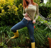 Hot ginger damsel posing in lingerie and rubber high boots in the garden