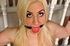 Ball gagged and tethered to the banister while sitting on the floor, blonde