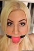 Ball gagged and tethered to the banister while sitting on the floor, blonde