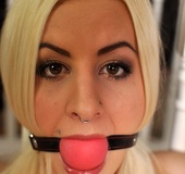 Ball gagged and tethered to the banister while sitting on the floor, blonde