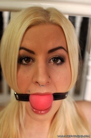 Ball gagged and tethered to the banister while sitting on the floor, blonde beauty seems to anticipate kinky hardcore action