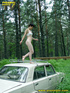 Daring brunette teen balances on a ladder proped on two cars, squats and