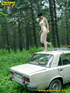 Daring brunette teen balances on a ladder proped on two cars, squats and