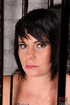 Short haired brunette slave wearing a fishnet body suit is kept inside
