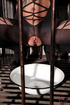 Short haired brunette slave wearing a fishnet body suit is kept inside
