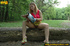 Cute chick sits on tree log in the woods and spreads legs to piss on magazine