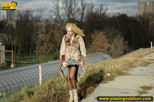 Sexy dressed blonde chick in boots walking on concrete road pissing outdoors - Picture 1