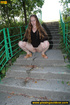 Smiling cute shapely chick in sexy black dress pisses along the park steps