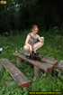 Long hair babe looking sweet climbs an old table in forest to spray hot