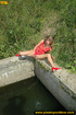 Lady in red with hot small tits hangs up on stone ledge to pee in water